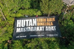 Groot spandoek met de tekst "Het bos wordt beter beschermd door de inheemse bevolking" (Nederlandse vertaling)