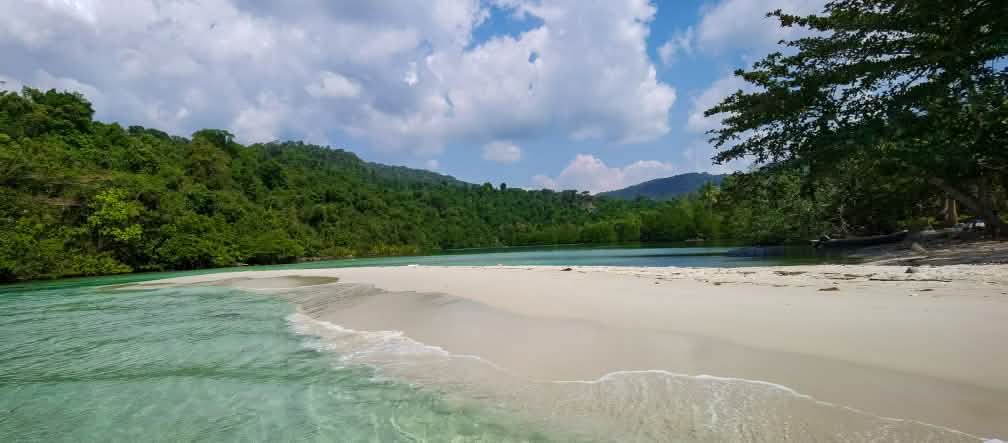 Een lagune op Koh Kong Island met helderwit zandstrand, op de achtergrond het bos