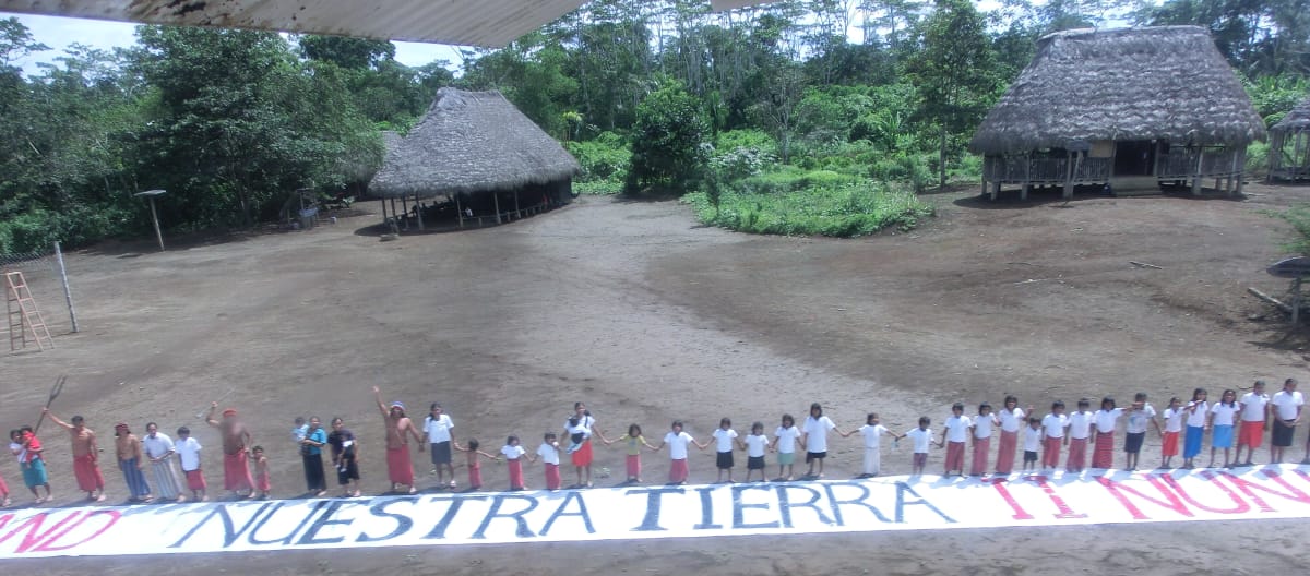 Ons land! – Nuestra tierra! Menselijke keten met spandoek tegen landroof in Ecuador