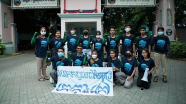 15 jongeren staan en knielen voor het gebouw van het ministerie van Toerisme en houden een spandoek voor de camera. Daarop staat: “Koh Kong Island moet een nationaal zeepark worden”