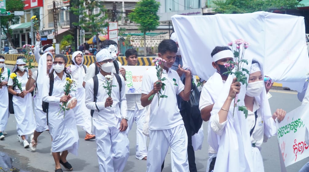 Jongeren gekleed in het wit lopen door een straat in Phnom Penh met bloemen in hun handen